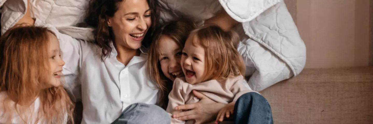 Mutter spielt mit Kindern unter einer Decke