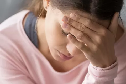 Frau ist schwindlich und hält sich den Kopf
