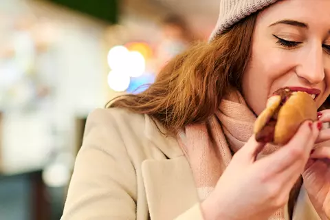 Frau isst eine Bratwurst im Brötchen