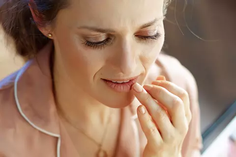 Frau streicht mit dem Finger über Ihre Lippen