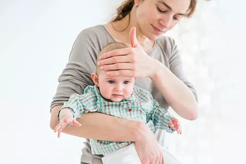 Eine Mutter mit einem erkältetem Baby macht sich auf dem Weg zum Arzt.