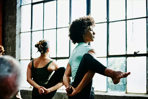 Eine junge Frau, die Schüßler verwendet, ist beim Yogatraining und übt das Balancieren.