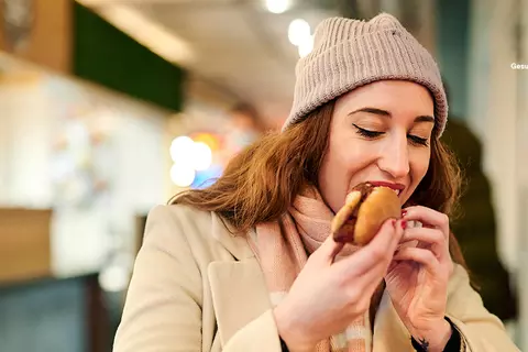 Frau isst eine Bratwurst im Brötchen