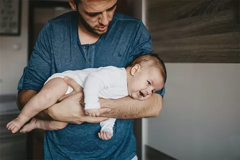 Vater hält sein Baby im Fliegergriff