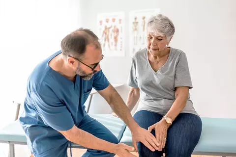 Seniorin mit Arthritis lässt sich beim Arzt untersuchen