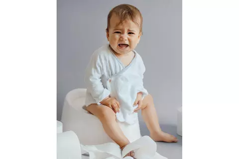 Baby sitzt mit Schmerzen auf dem Töpfchen