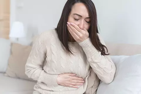 Frau sitzt auf der Couch und ist schlecht