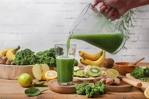 Glas mit grünem Saft aus verschiedenem Obst und Gemüse