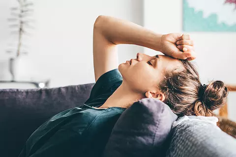 Eine junge Frau liegt erschöpft auf der Couch