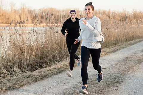 2 Frauen joggen in kaltem Wetter an einem Ufer entlang