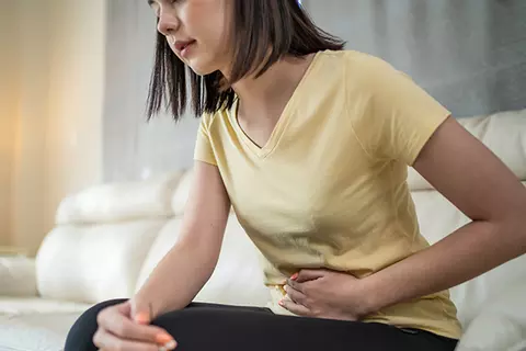 Frau hält sich wegen Bauchschmerzen die Hand an den Magen