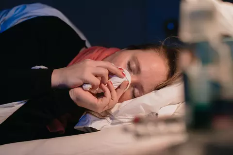 Frau liegt krank im Bett