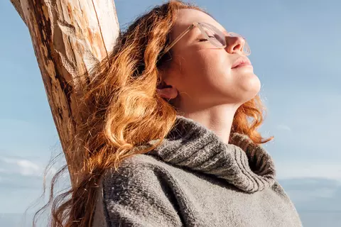 Frau genießt die Sonne und hat die Augen geschlossen