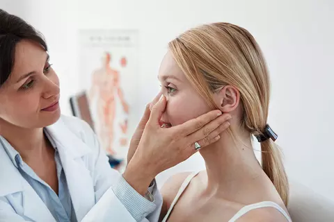 Ärztin untersucht der Patientin Wange und Stirn
