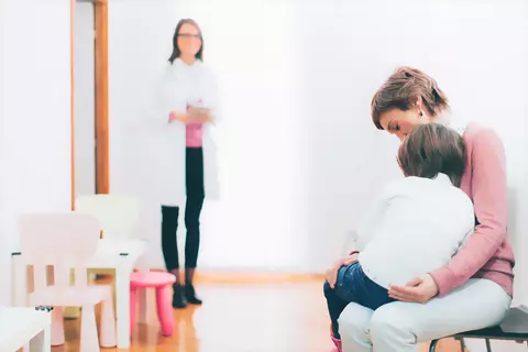 Mutter mit Kind im Wartezimmer einer Arztpraxis