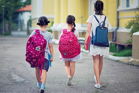 Kinder mit schweren Schulranzen auf dem Weg zur Schule