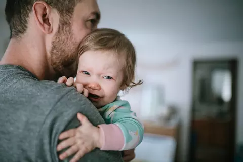 Vater hält Kind weinendes Kind auf dem Arm