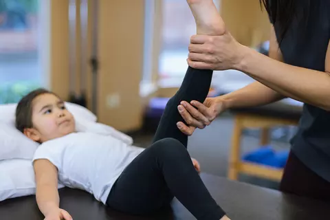 Mutter massiert das Bein ihres Kindes