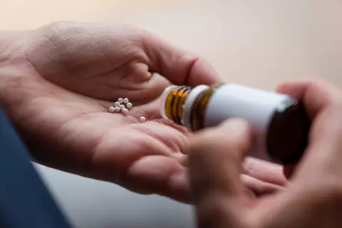 Globuli werden auf die Hand gestreut.