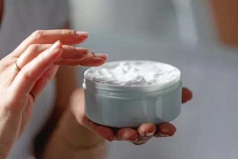 Hand hält eine Cremedose