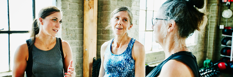 Drei Frauen unterhalten sich im Fitnessstudio