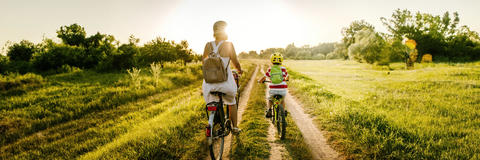 Mutter und Kind fahren mit dem Rad über ein Feld