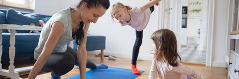 Mutter macht zusammen mit den Kindern Sport im Wohnzimmer