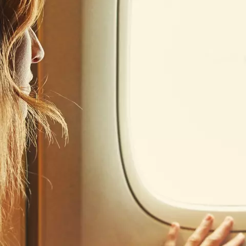 Frau sitzt im Flugzeug und hat Angst
