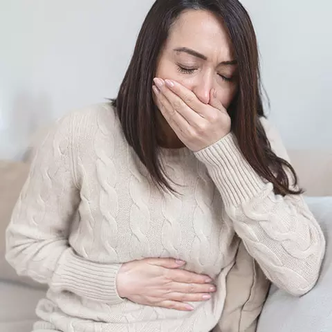 Frau sitzt auf der Couch und ist schlecht