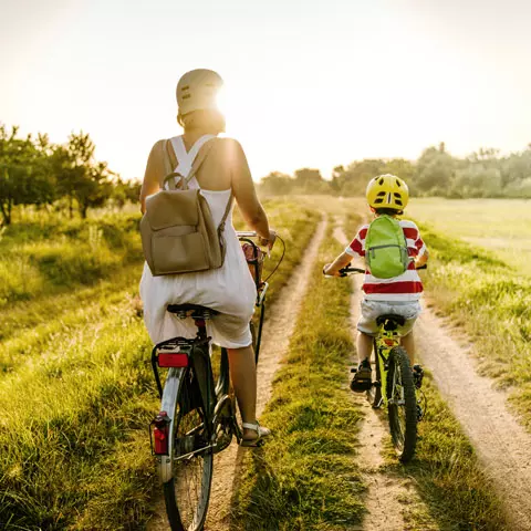 Mutter und Kind fahren mit dem Rad über ein Feld