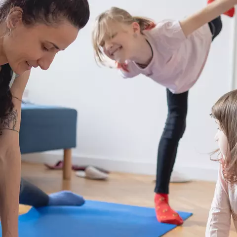 Mutter macht zusammen mit den Kindern Sport im Wohnzimmer