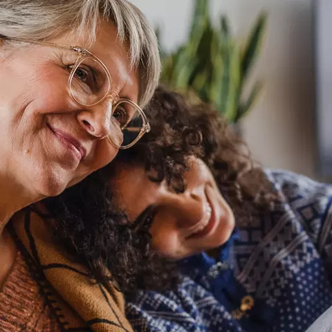 Seniorin und Enkel sitzen Tee und Decke zusammen