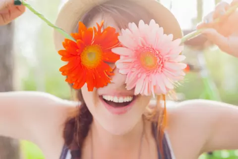 Frau hebt sich Blumen vors Gesicht