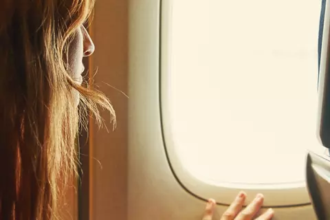 Frau sitzt im Flugzeug und hat Angst