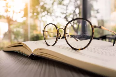 Eine Brille liegt auf einem aufgeschlagenen Buch