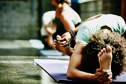 Eine junge Frau, die Schüssler verwendet, dehnt gerade ihren Körper beim Yogaunterricht.