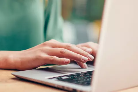 Frau sitzt mit Kaffee am Laptop