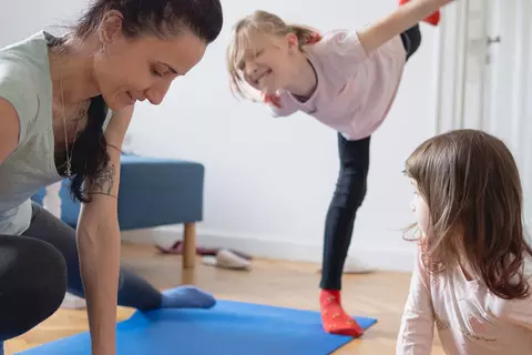 Mutter macht zusammen mit den Kindern Sport im Wohnzimmer