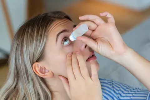 Frau tropft ihr Auge mit Augentropfen