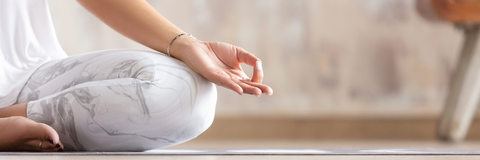 Frau sitzt auf einer Yoga-Matte und meditiert