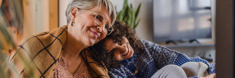 Seniorin und Enkel sitzen Tee und Decke zusammen