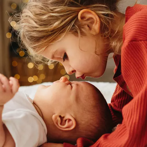 Kleines Kind küsst Baby auf die Stirn
