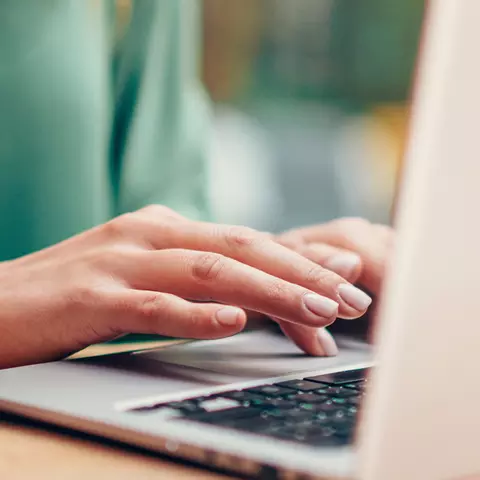 Frau sitzt mit Kaffee am Laptop
